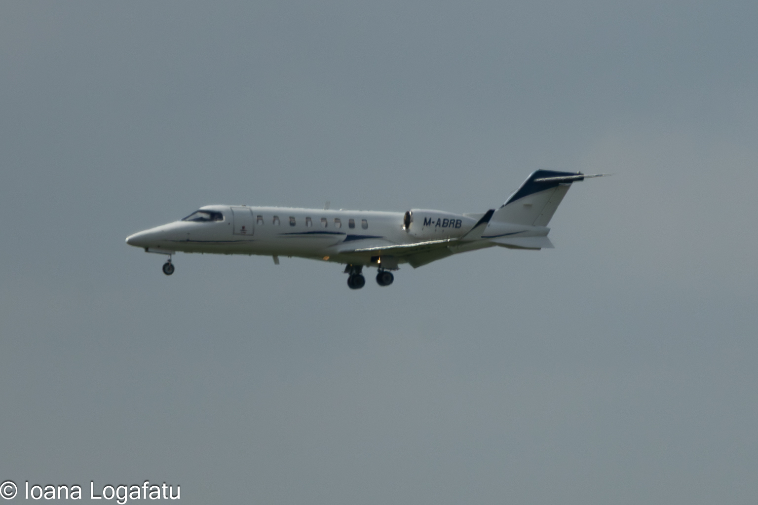 Private jet glides through a cloudy sky above city